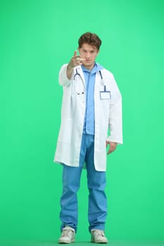 The doctor, in full height, on a green background, points forward.