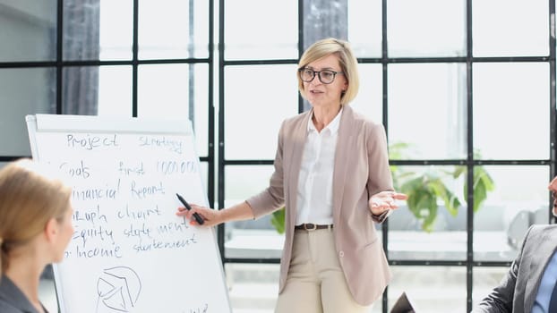 Beautiful young businesswoman writing on blank whiteboard in office