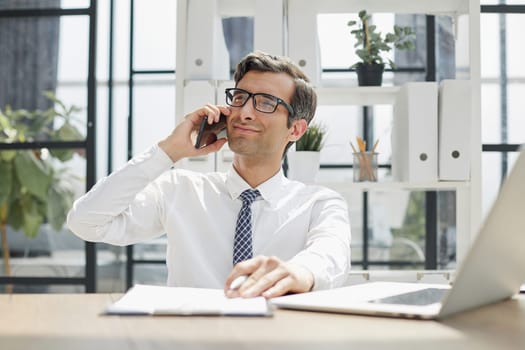 Man accountant or business lawyer talking on smartphone with finance paperwork at workplace