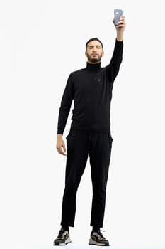 A man, full-length, on a white background, waving his phone.