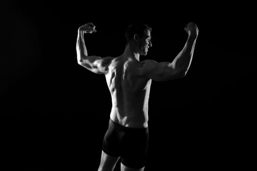 Handsome bodybuldier man posing showing muscle, shirtless torso showing pectorals and sixpacks
