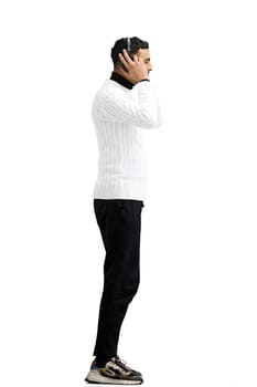 A man, full-length, on a white background, listening to music in headphones.