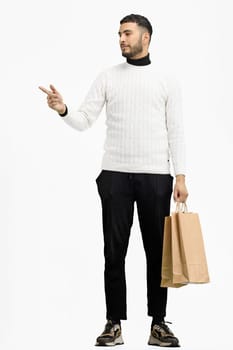 A man, full-length, on a white background, with bags, points to the side.