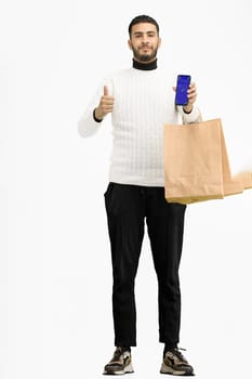 A man, full-length, on a white background, with bags, shows a phone.