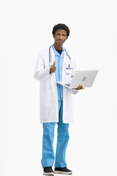 The doctor, in full height, on a white background, uses a laptop.