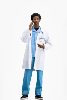 The doctor, in full height, on a white background, talking on the phone.