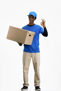 The deliveryman, in full height, on a white background, with a box, shows the ok sign.