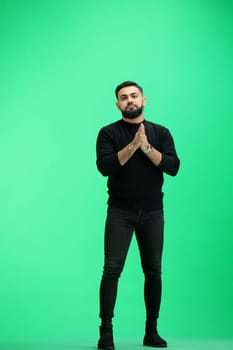 A man, full-length, on a green background, folded his arms.