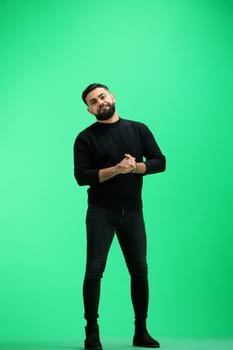 A man, full-length, on a green background, folded his arms.