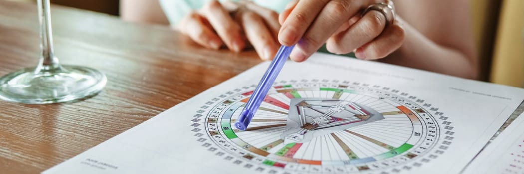 Tver, Russia - August 2, 2021. A woman in a cafe at a table is studying the design of a person. The concept of studying esoteric sciences. A bodigraph or a map of a person on an A4 sheet