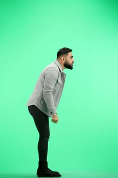 A man, full-length, on a green background, spreads his arms.