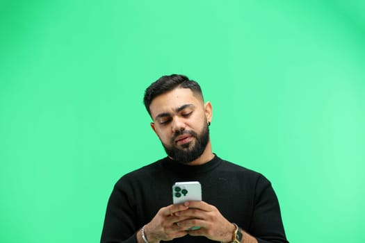 Man, close-up, on a green background, using a phone.