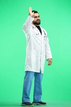 The doctor, in full height, on a green background, waving his hand.