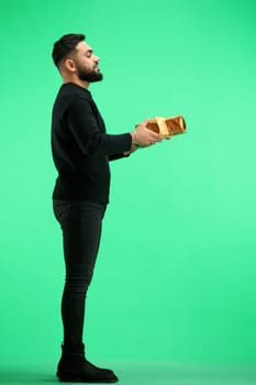 A man, full-length, on a green background, with a gift.