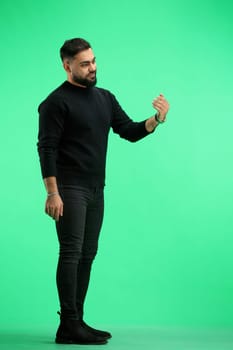 A man, full-length, on a green background, calls to him.