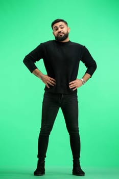 Man, full-length, on a green background, hands on hips.