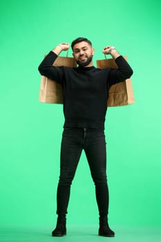 A man, full-length, on a green background, with bags.