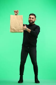 A man, full-length, on a green background, with bags.