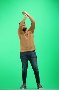 A man, full-length, on a green background, claps.
