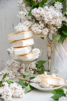 spring still life with a bouquet of white lilacs, a stack of waffle ice cream in a bowl and on a saucer, vintage ceramic dishes, high quality photo