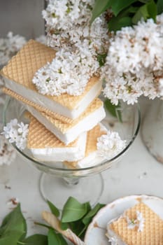 spring still life with a bouquet of white lilacs, a stack of waffle ice cream in a bowl and on a saucer, vintage ceramic dishes, high quality photo