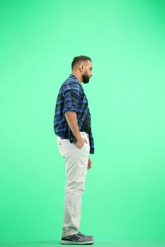 A man, full-length, on a green background.