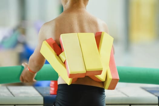 A kid with a swimming float belt in a swimming pool