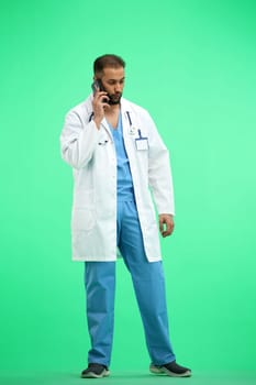 The doctor, in full height, on a green background, talking on the phone.