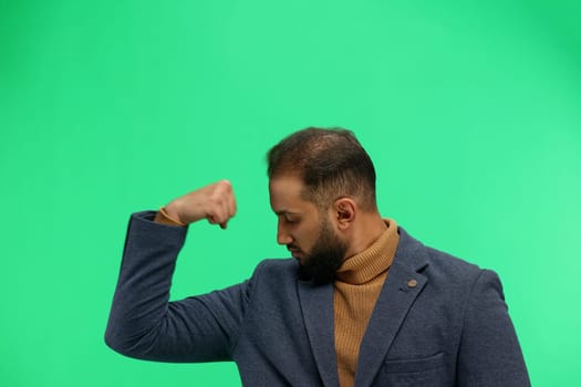 Man, close-up, on a green background, shows strength.