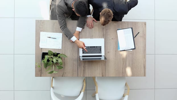 two businessmen sitting on a chair and watching something on a laptop