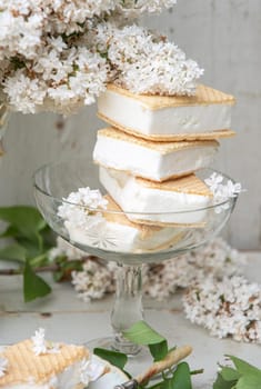 spring still life with a bouquet of white lilacs, a stack of waffle ice cream in a bowl and on a saucer, vintage ceramic dishes, high quality photo