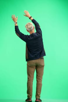 A man, full-length, on a green background, waving his arms.