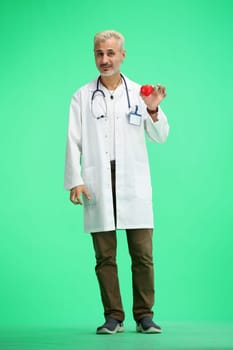 The doctor, in full height, on a green background, shows the heart.