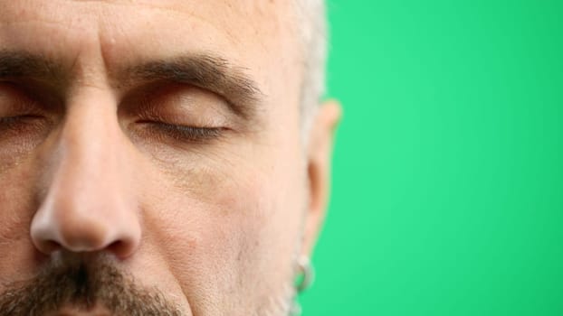 Man's eyes, close-up, on a green background.