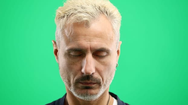Man's face, in close-up, on a green background.
