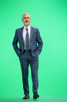 A man, full-length, on a green background.