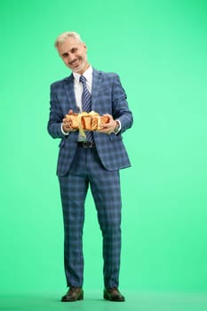 A man, full-length, on a green background, with a gift.