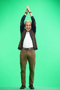 A man, full-length, on a green background, claps.