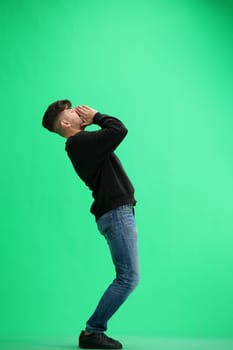 A man, full-length, on a green background, rejoices.