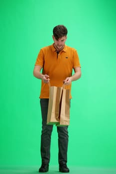 A man, full-length, on a green background, with bags.