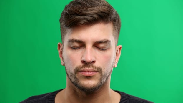 Man's face, close-up, on a green background.