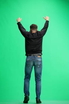 A man, full-length, on a green background, rejoices.