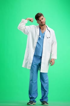 The doctor, in full height, on a green background, shows strength.