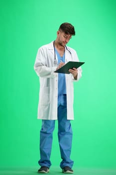 The doctor, in full height, on a green background, writes.
