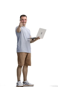 A man in a gray T-shirt, on a white background, in full height, uses a laptop.