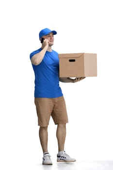 Male deliveryman, on a white background, full-length, with a phone and box.