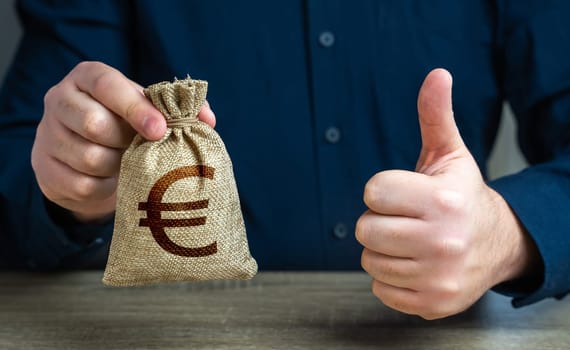 Thumbs up and euro money bag. The man approves the deal or loan. Agreement to be hired for a job at the offered salary. Profit-generating deposits savings.