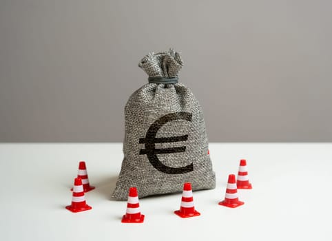Euro money bag blocked by road cones. Suspicious funds with unknown sources. National money reserve. Freezing of accounts and sanctions on capital.