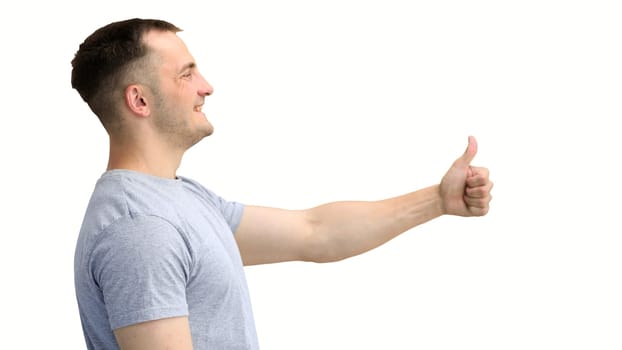 A man in a gray T-shirt, on a white background, close-up, shows his thumbs up.
