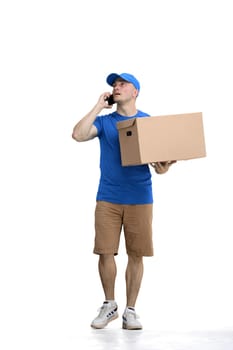 Male deliveryman, on a white background, full-length, with a phone and box.
